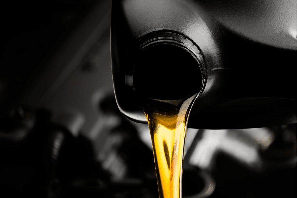 auto maintenance, auto repair in Tea, SD at Sioux Empire Automotive Service Center. Golden motor oil being poured from a black container into an engine, emphasizing the importance of regular oil changes for vehicle maintenance.