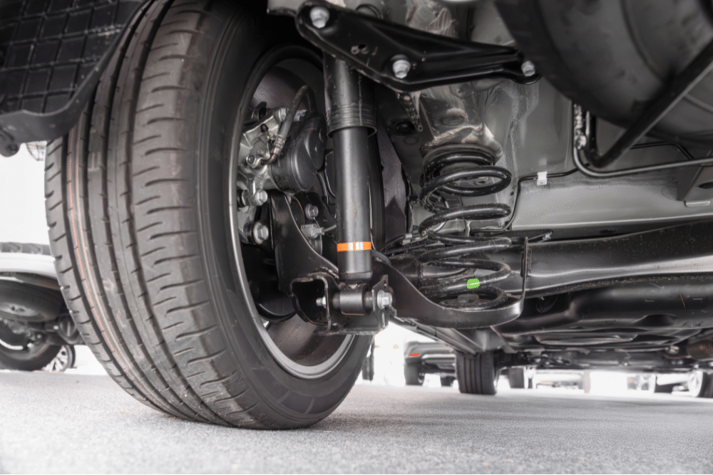 suspension repair, auto repair in Tea, SD at Sioux Empire Automotive Service Center. Underbody view of a vehicle’s wheel, shock absorber, and suspension system, showcasing attention to safety and performance.