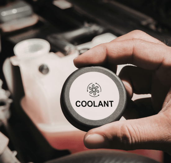 Antifreeze vs. Coolant in Tea, SD by Sioux Empire Automotive Service Center. Image of a technician holding a coolant reservoir cap labeled “Coolant” above the engine bay, highlighting coolant level checks to help prevent overheating and protect engine performance.