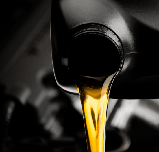 auto maintenance, auto repair in Tea, SD at Sioux Empire Automotive Service Center. Golden motor oil being poured from a black container into an engine, emphasizing the importance of regular oil changes for vehicle maintenance.